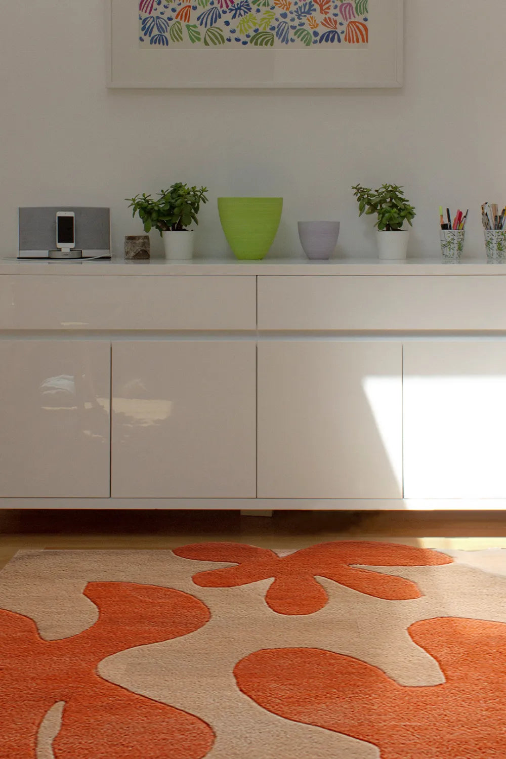 Modern wool rug in abstract orange shapes in a bright bedroom, suited for boutique 5x7 area rugs or hallways