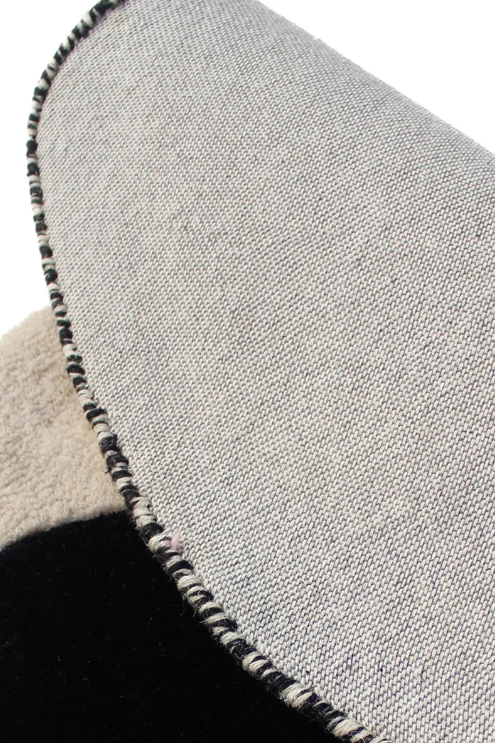 Close-up of hand-tufted black and white wool rug showing durable cotton backing and fine edging