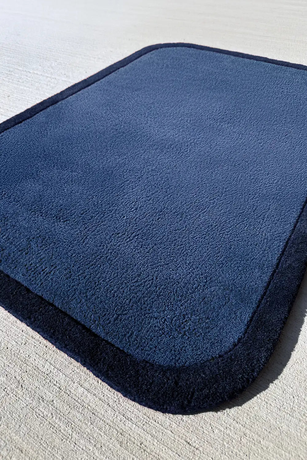 Thick plush navy blue wool rug with soft rounded corners, perfect for colorful modern interiors
