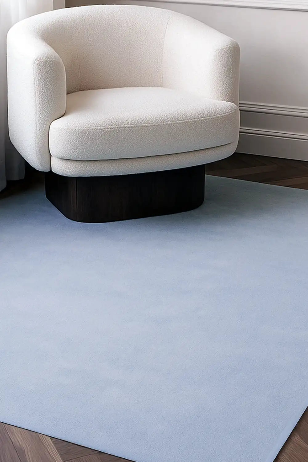Light blue wool rug in 8x10 size styled under a cream armchair, perfect for minimalist living rooms or bedroom rugs lifestyle