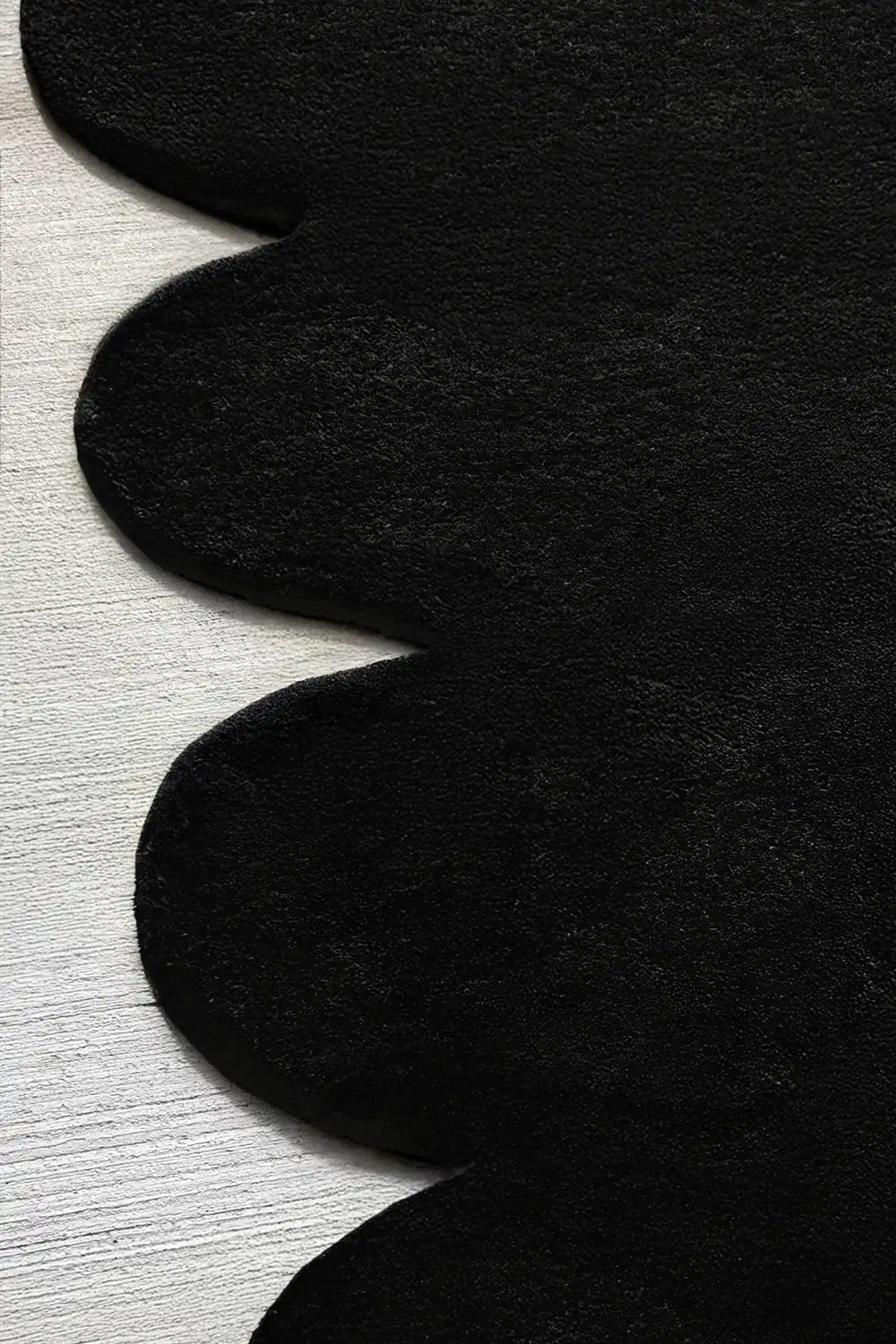 Sculpted black wool rug with bold scalloped edge design, hand-tufted for soft texture and visual impact