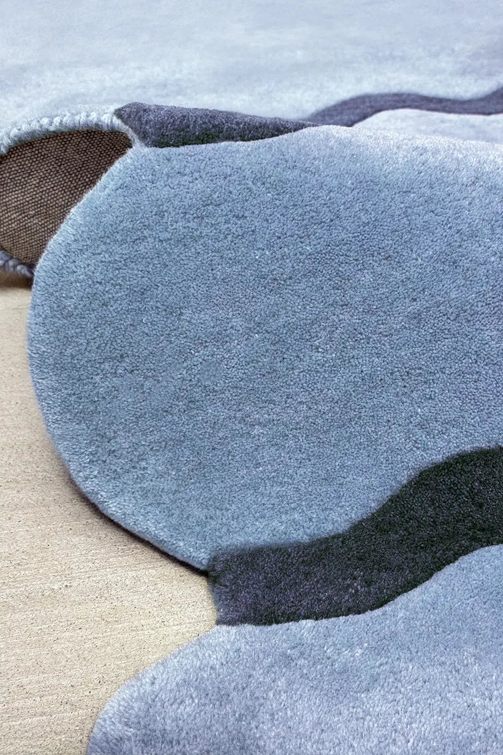 Folded view of modern tufted ripple wool rug, abstract sculptural area rug blue