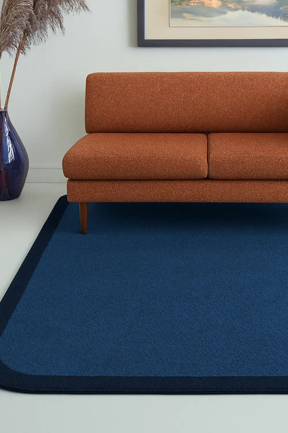 Navy blue wool rug with black border and rounded edges, styled in a bold colorful modern living room