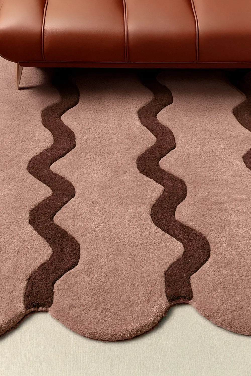 Tan ripple wool rug styled near brown leather sofa, mid-century modern area rug lifestyle