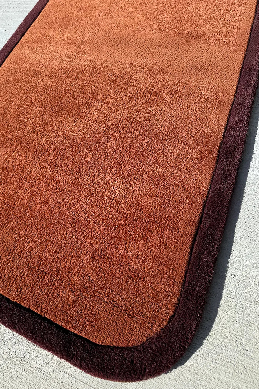 Hand-tufted rust wool runner with rounded dark trim, cozy earth tone hallway rug