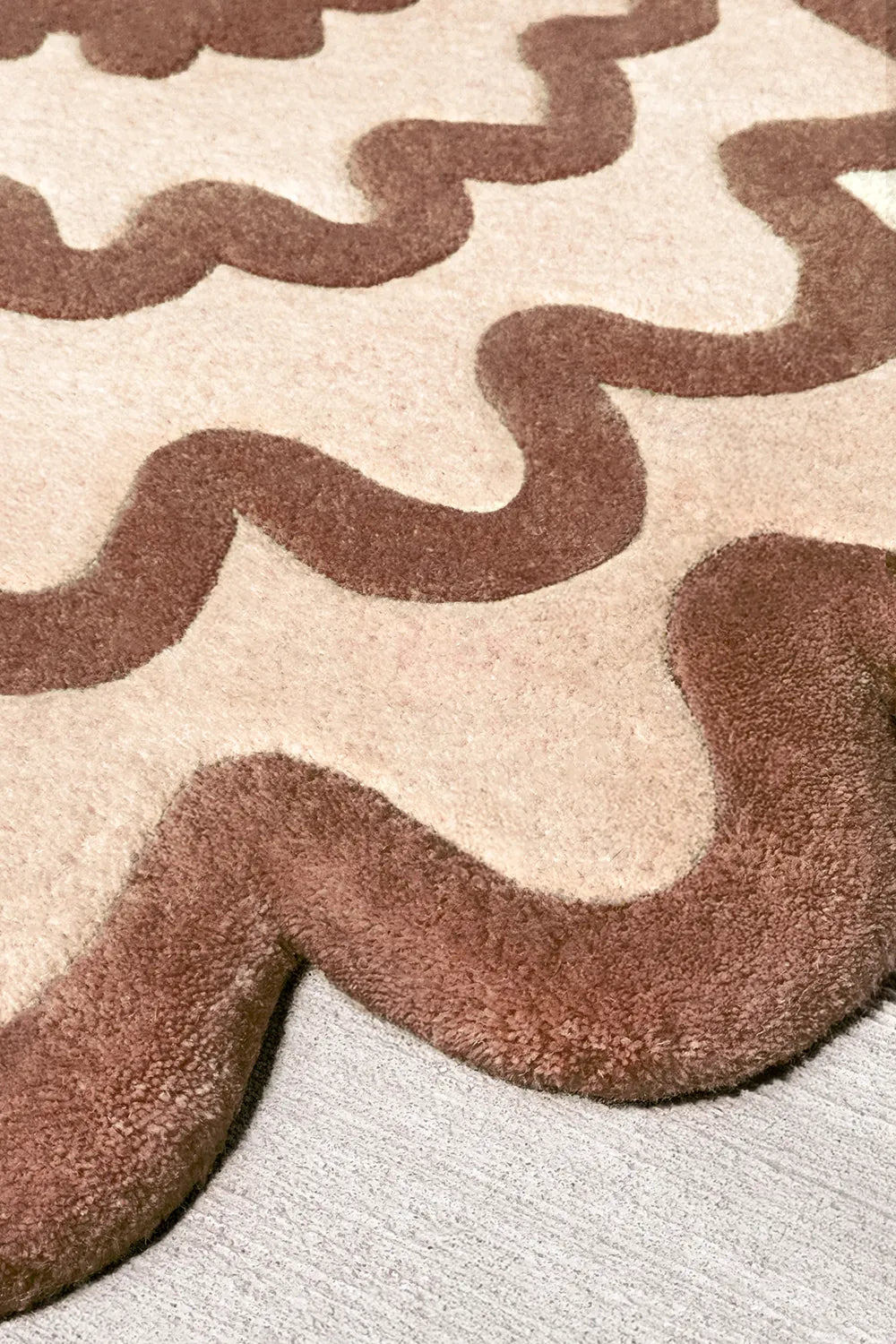 Textured close-up of brown and beige modern ripple wool rug, funky neutral oval rug design