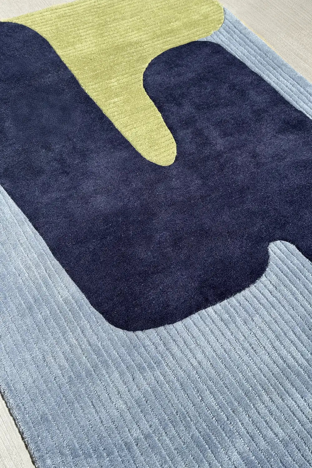 contemporary abstract wool rug in 5x7 with sculpted blue, navy, chartreuse, and green shapes
