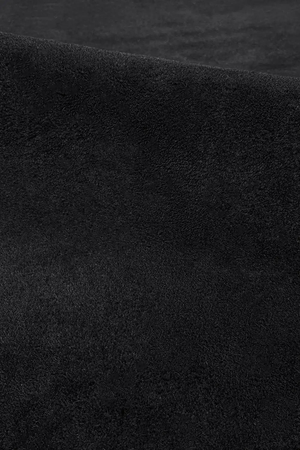 Close-up of plush black wool rug surface showing hand-tufted pile and smooth velvety texture oreo