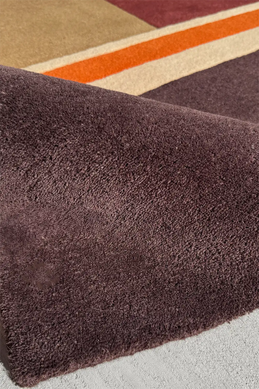 Luxury striped rug in deep brown and red tones with an earthy wool texture