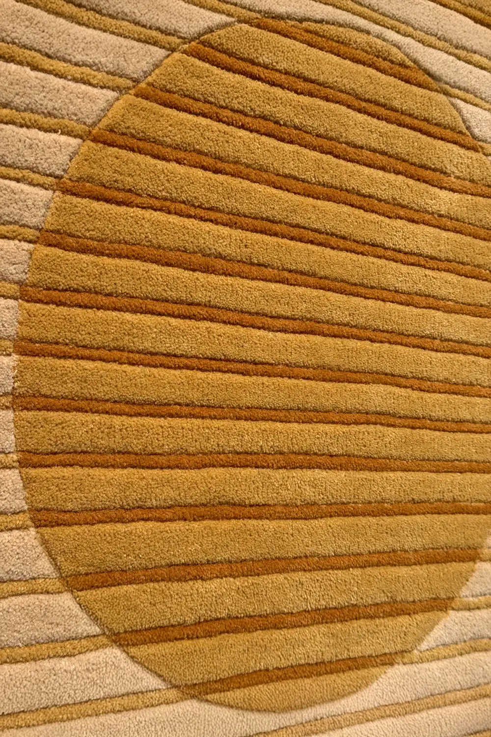 Close-up of a textured gold and beige rug with concentric circle pattern