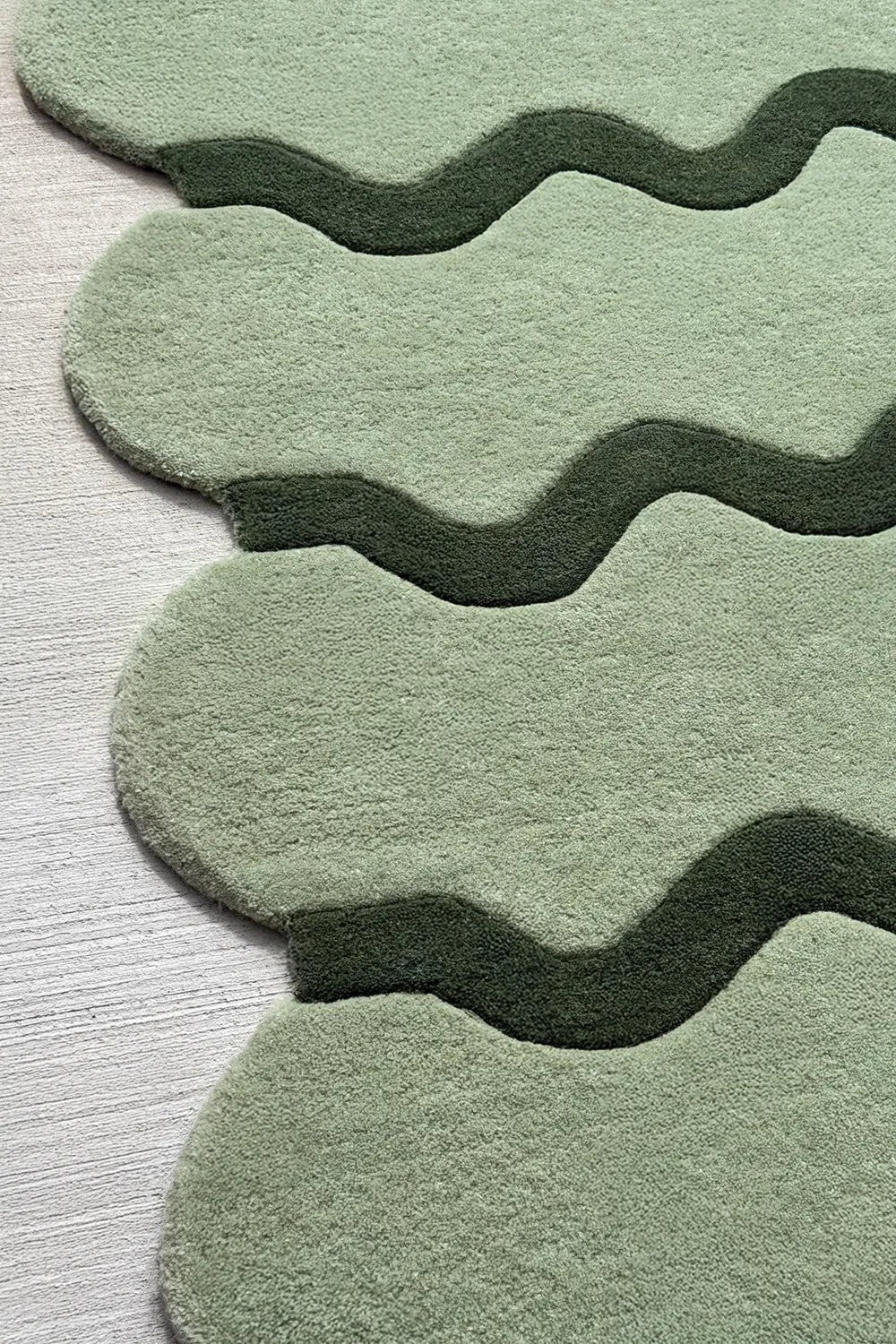 Close-up of sculptural wavy sage green wool rug highlighting hand-tufted craftsmanship