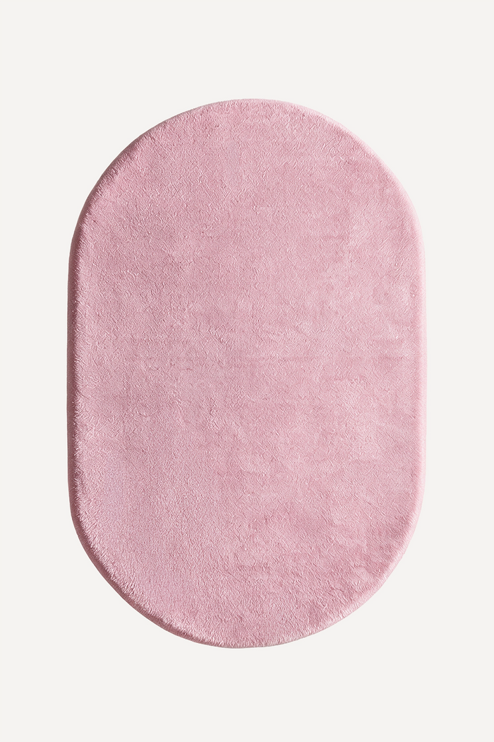 soft light pink oval rug on a white background