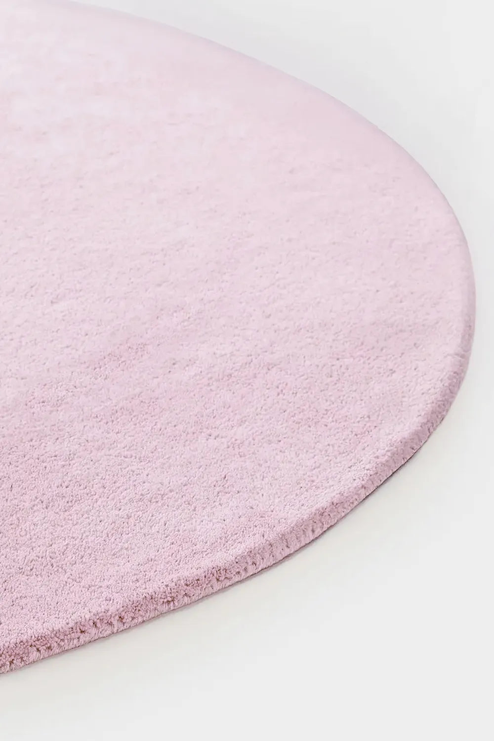 Close-up of soft tufted baby pink wool round rug, perfect for kids rooms and nurseries