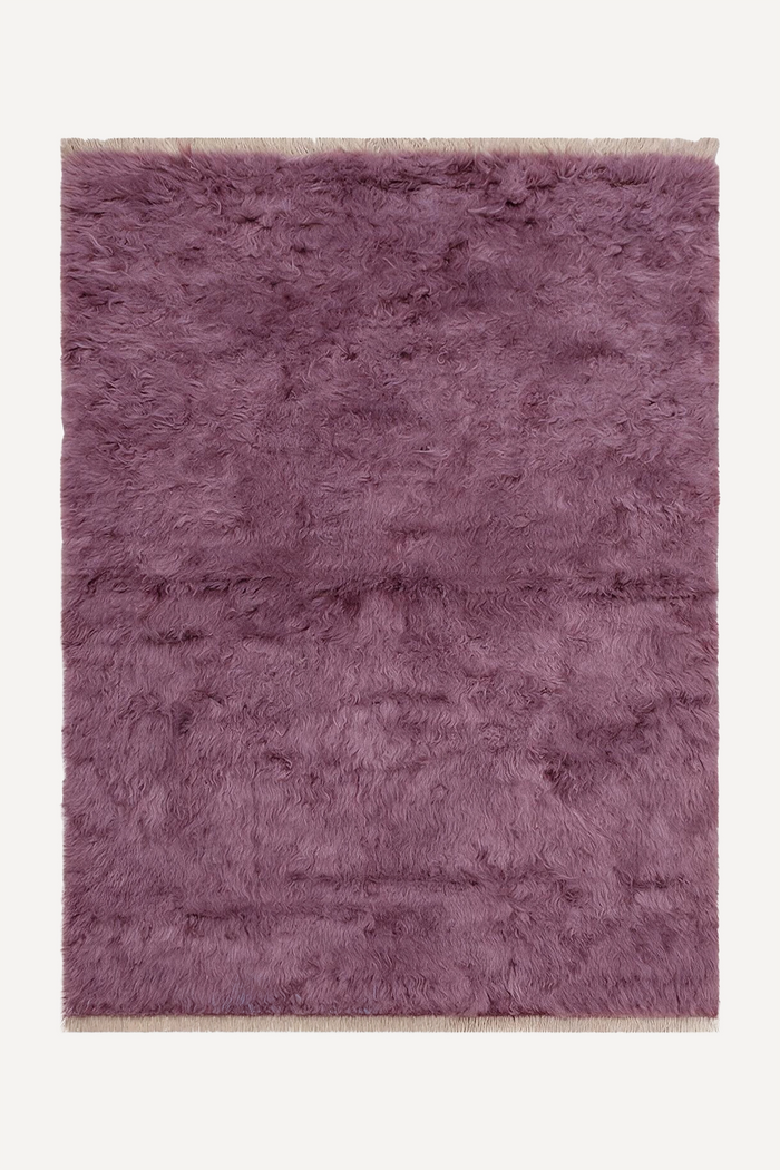 A rectangular shaggy area rug in a dusty mauve-purple color, shown flat against a clean off-white background.