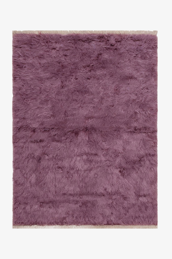 A rectangular shaggy area rug in a dusty mauve-purple color, shown flat against a plain white background.