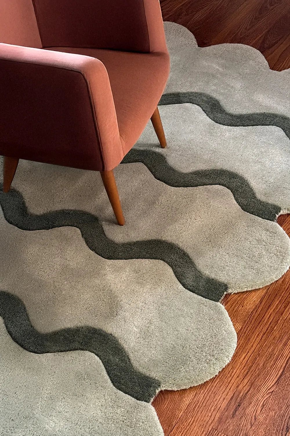 Boho sage green ripple area rug styled under burnt orange accent chair, modern 8x10 rug lifestyle