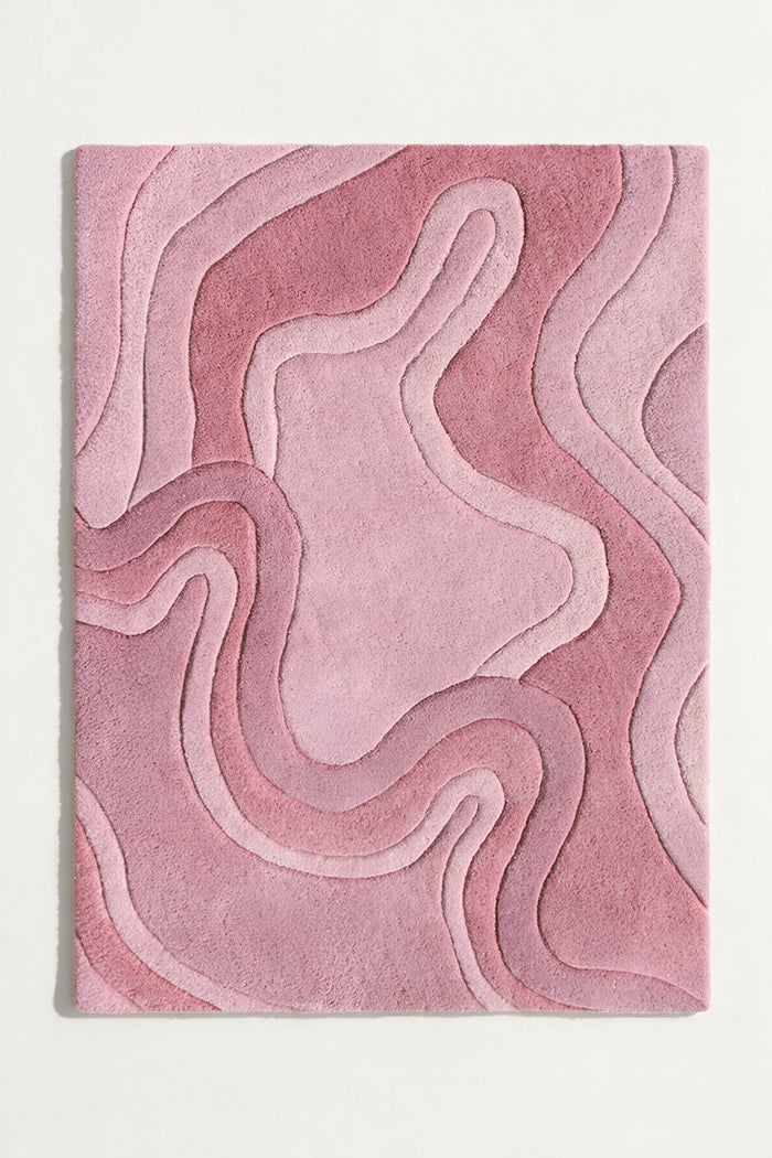 A rectangular area rug with an abstract, layered topographic pattern in shades of dusty pink and mauve, shown flat against a light gray background rose