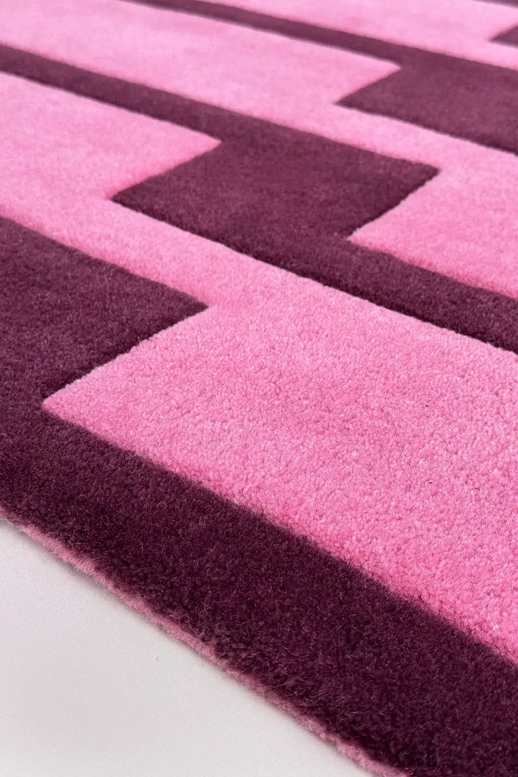 Close-up of a pink and purple geometric patterned wool rug.