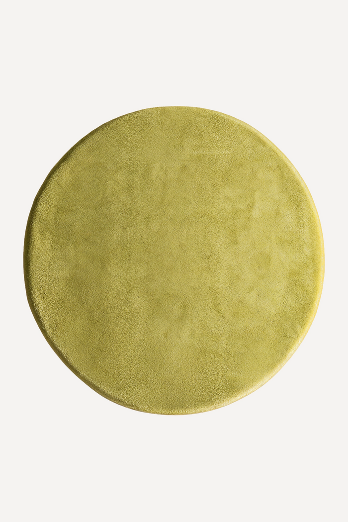 Round lime green wool rug on a white background