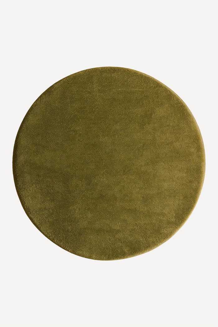 Round dark olive green wool rug on a white background