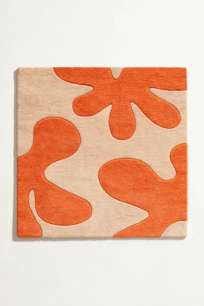 square rug with orange and beige abstract pattern on a white background