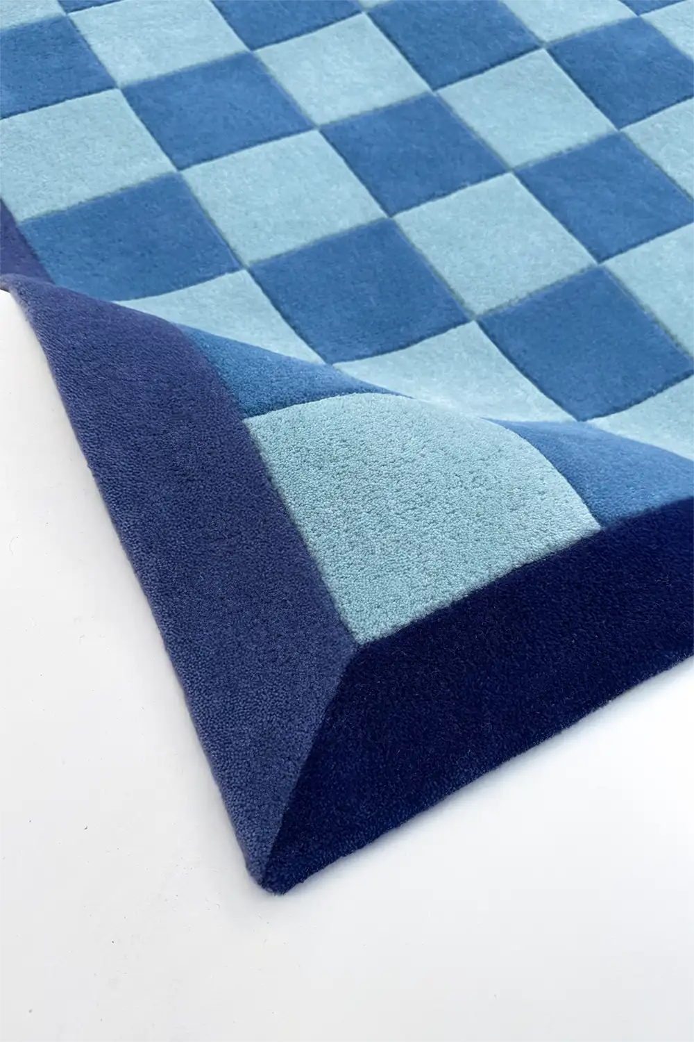 Blue checkered tufted wool rug on a white background