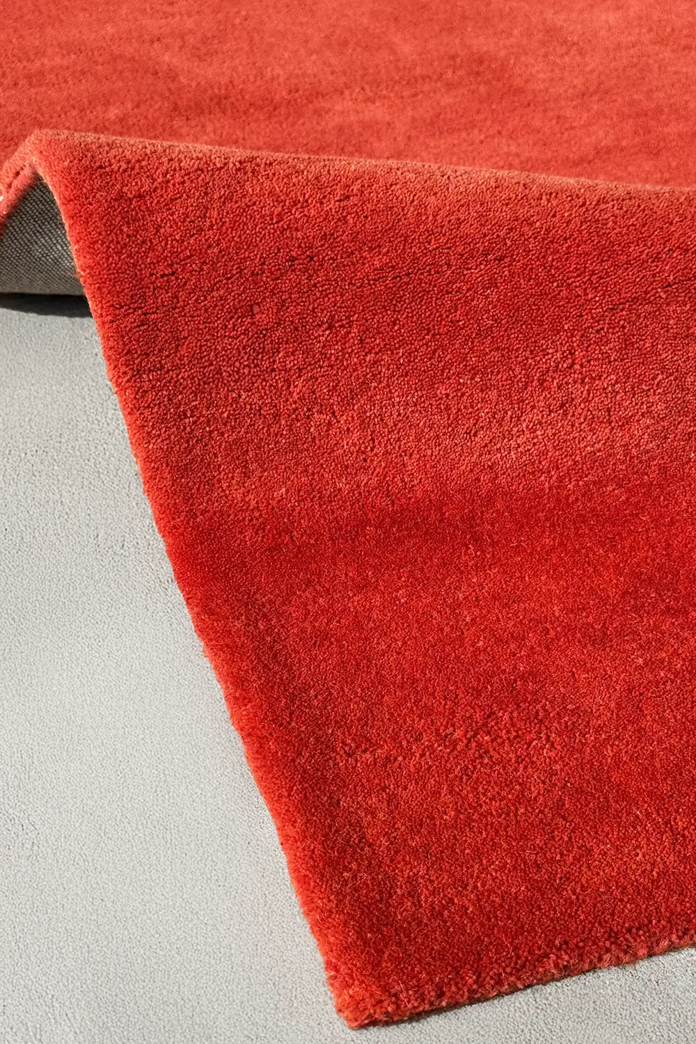 Close-up of a red wool rug on a light gray floor