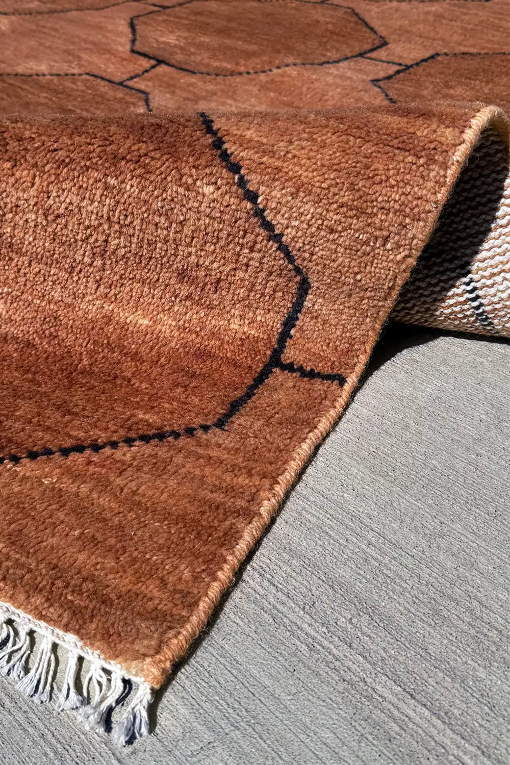 texture detail of a brown hand knotted wool rug with geometric pattern