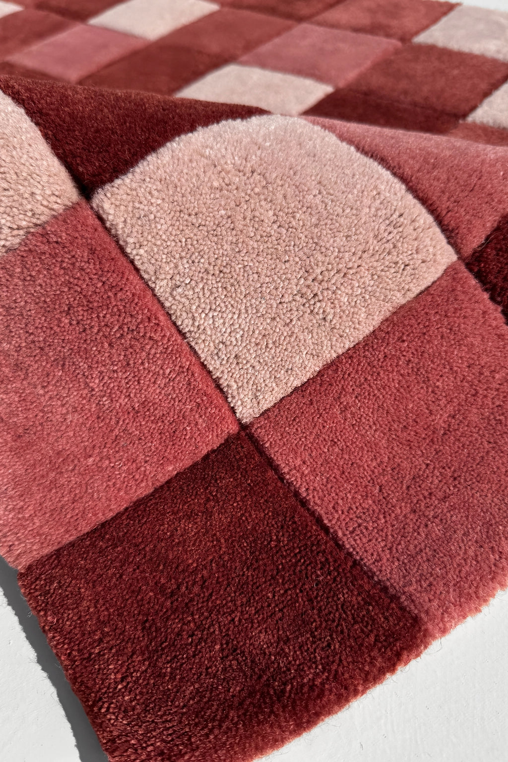 Checkered rug with red and beige squares texture on a white background