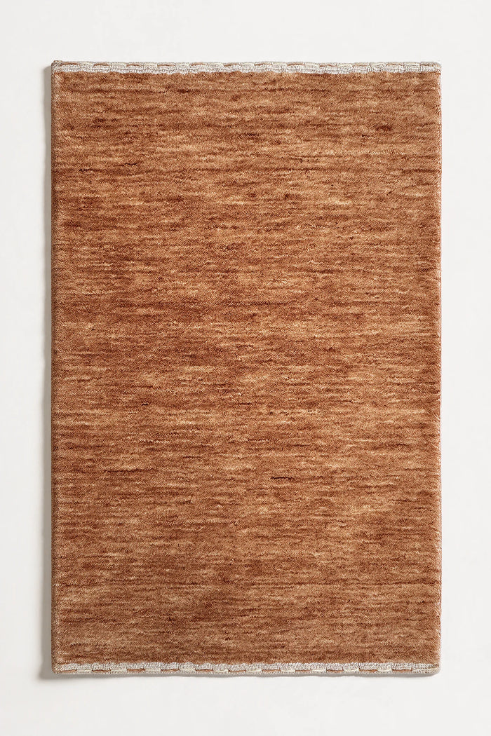 warm camel brown textured wool rug on a white background