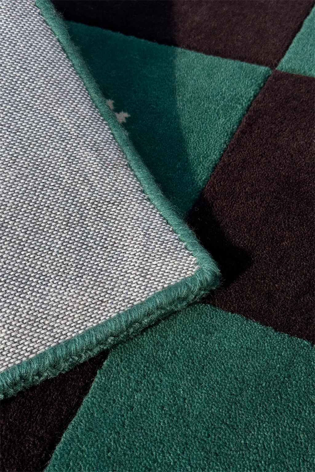 Close-up of a geometric-patterned rug with green, black, and gray colors.