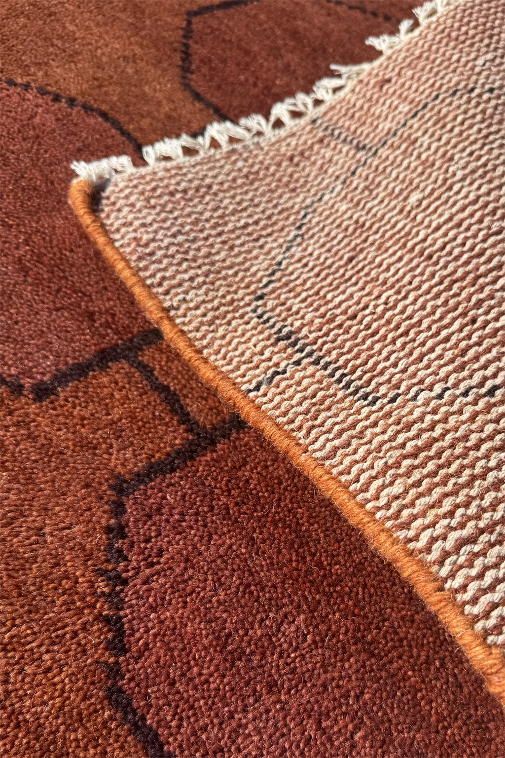 Close-up of a textured rug with chestnut and beige colors.