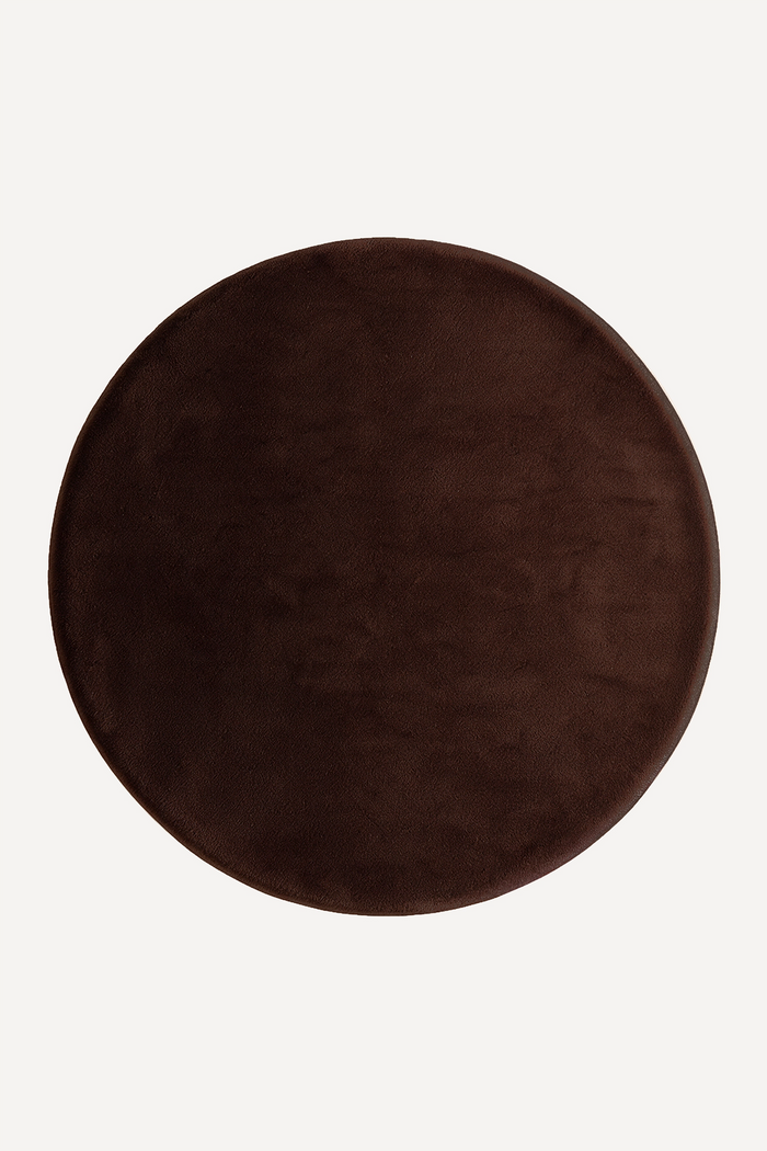 A round dark brown plush rug shown from a top-down view on a light off-white background.