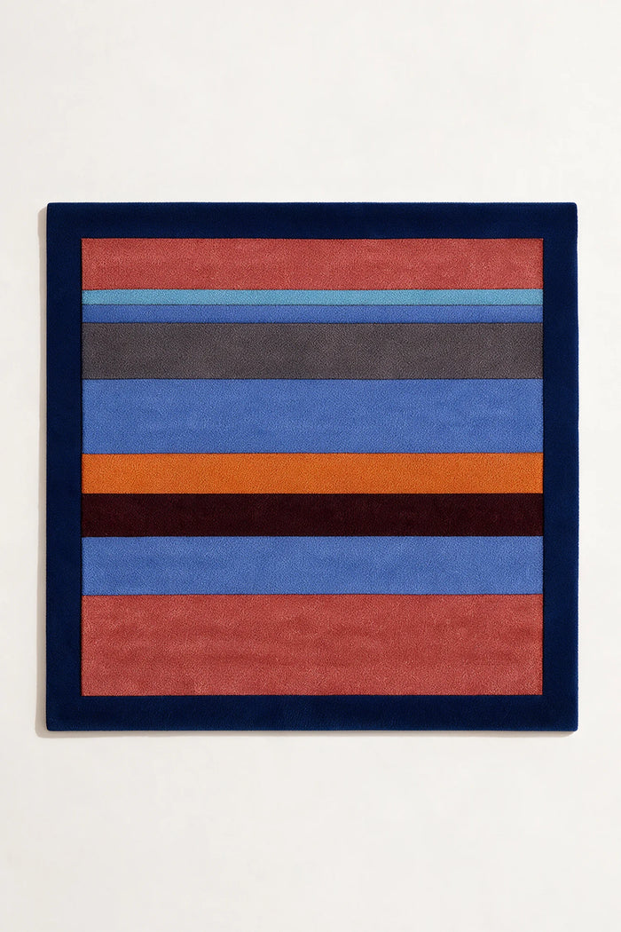 square wool rug with horizontal stripes in red, blue, orange, and gray with a navy border on a white background