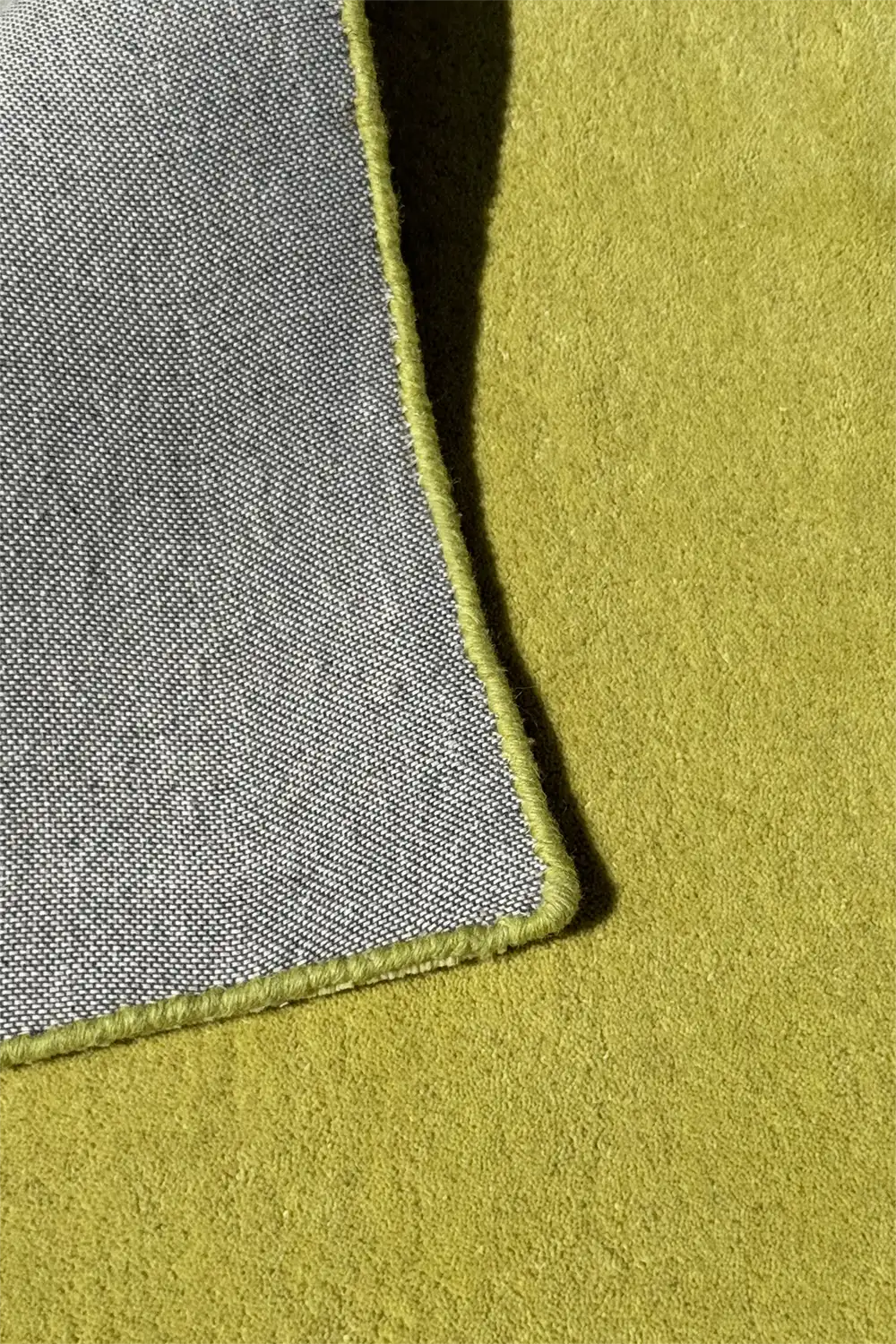 Close-up of a lime green area rug surface with a textured gray back.