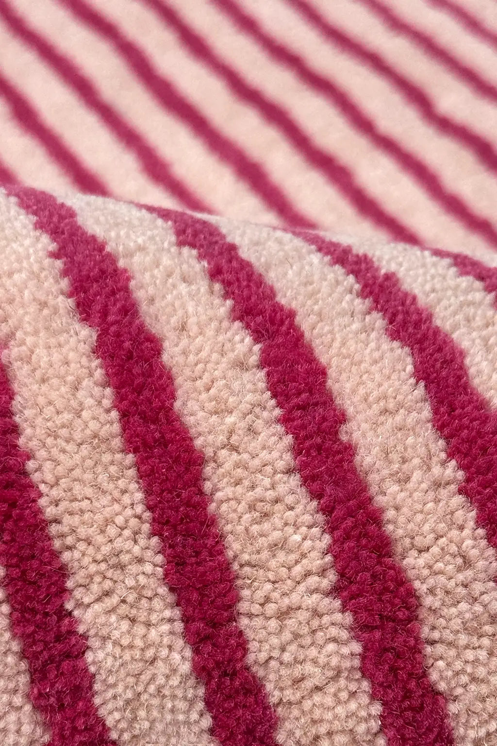 Close-up of a vibrant pink and beige striped wool rug texture
