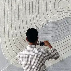 Person hand-tufting a textured rug with circular patterns.