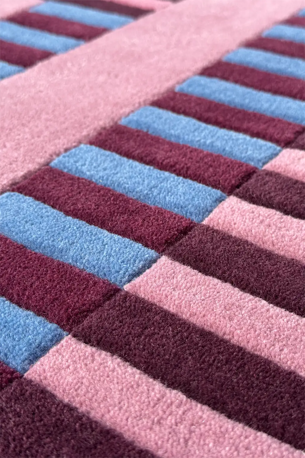 Close-up of a textured rug with pink and blue striped pattern