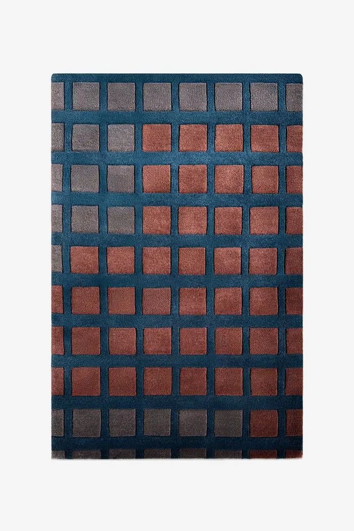 geometric rug with a checkered pattern in rust and gray with deep teal blue borders