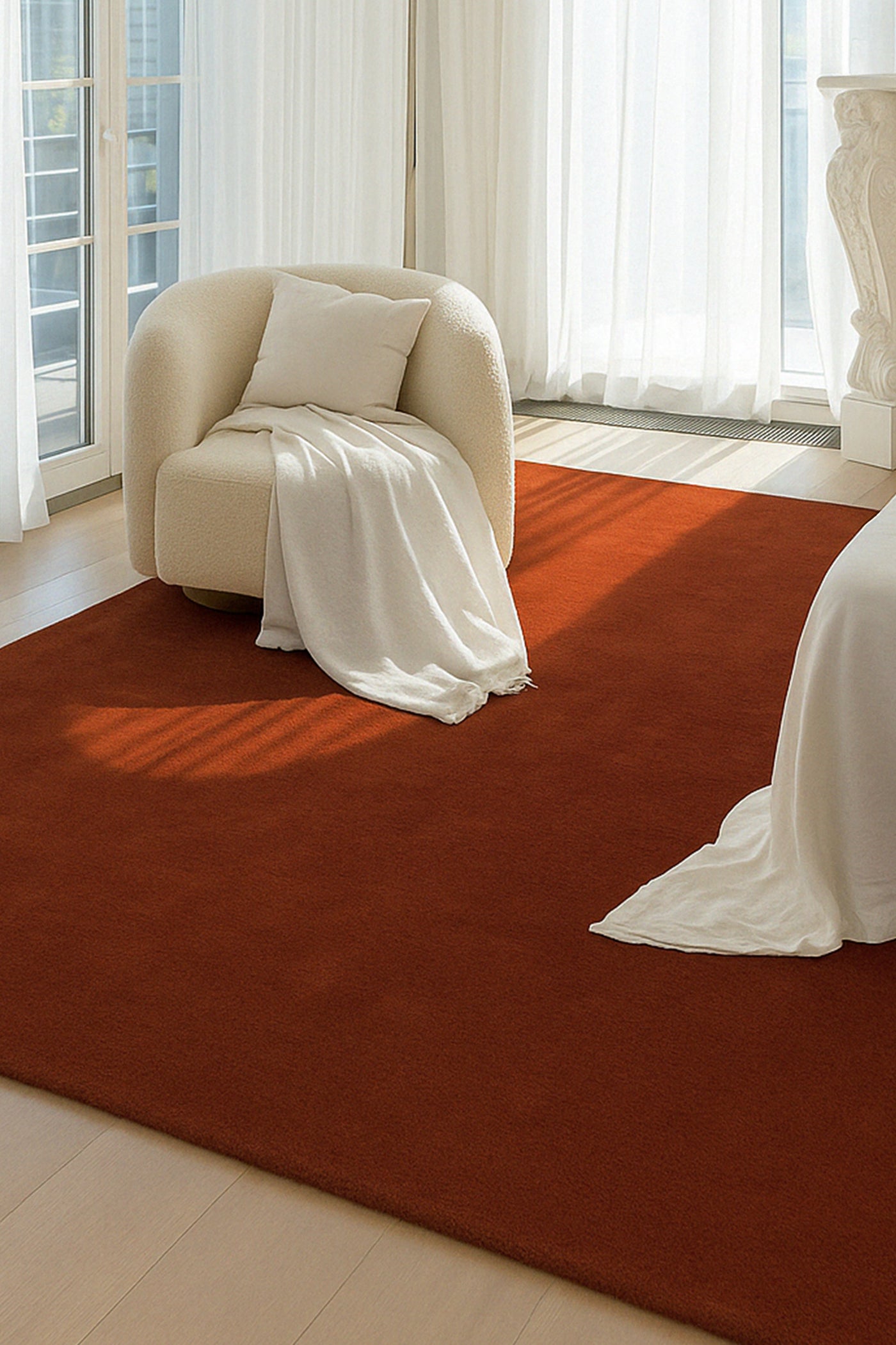 Burnt orange wool rug in bright open bedroom with white chairs and curtains, modern mid century area rug