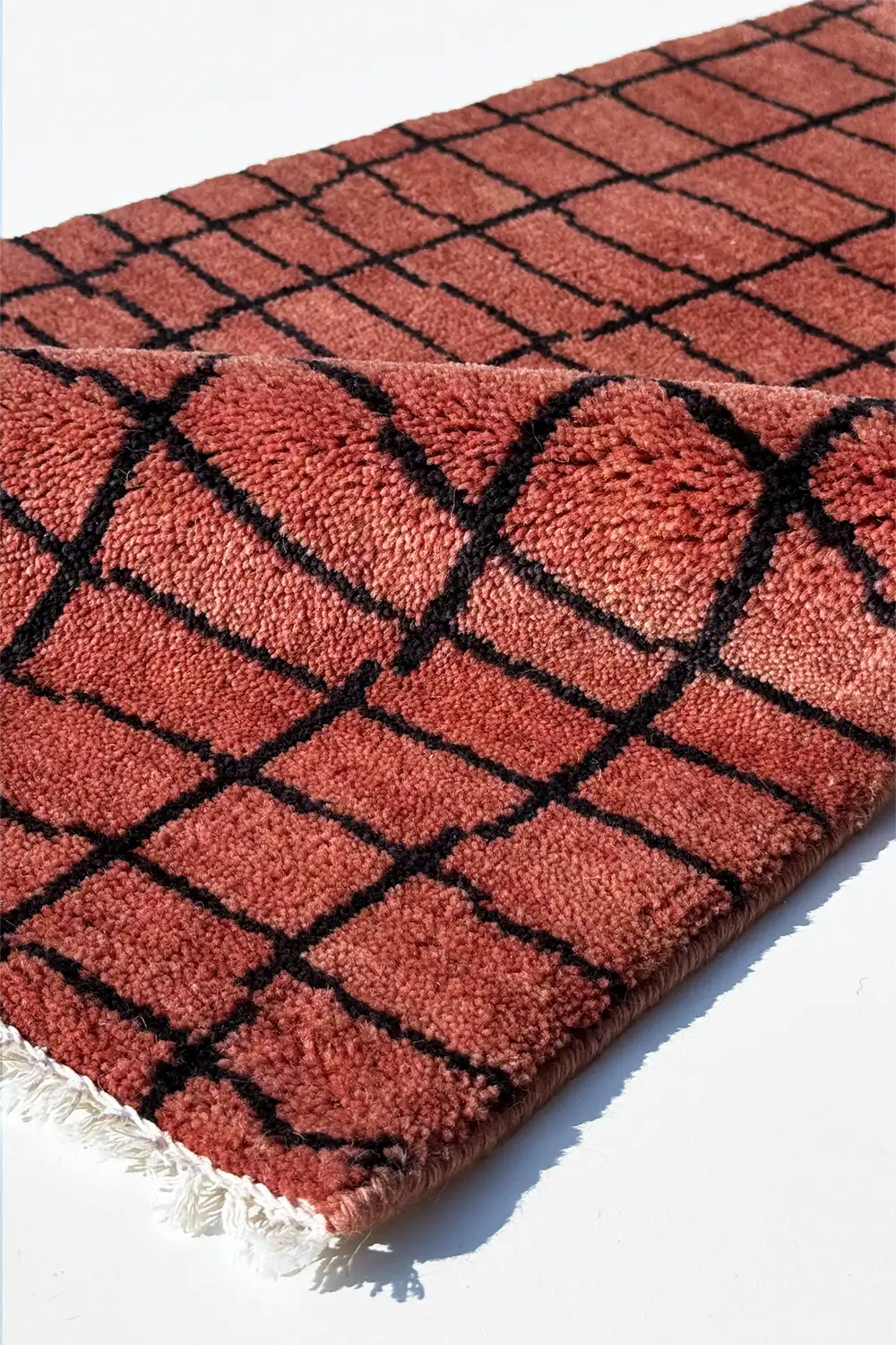 rust rug with black geometric pattern on a white background