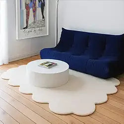 Modern living room with a blue sofa, white coffee table, and decorative scalloped rug.