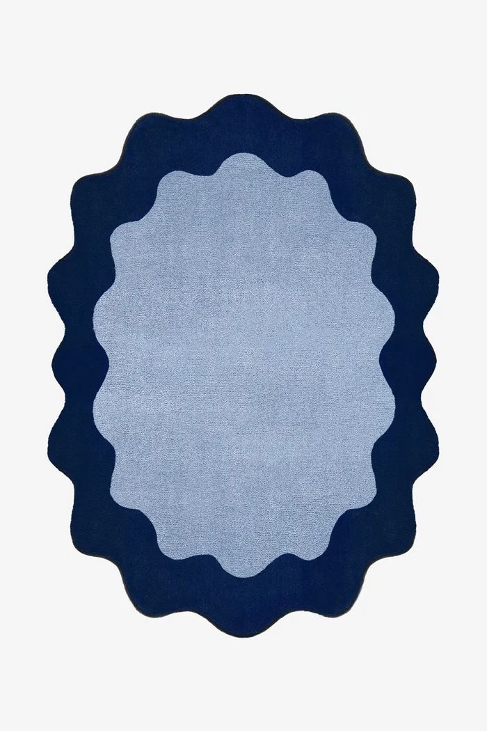 oval blue rug with navy scalloped edge on a white background