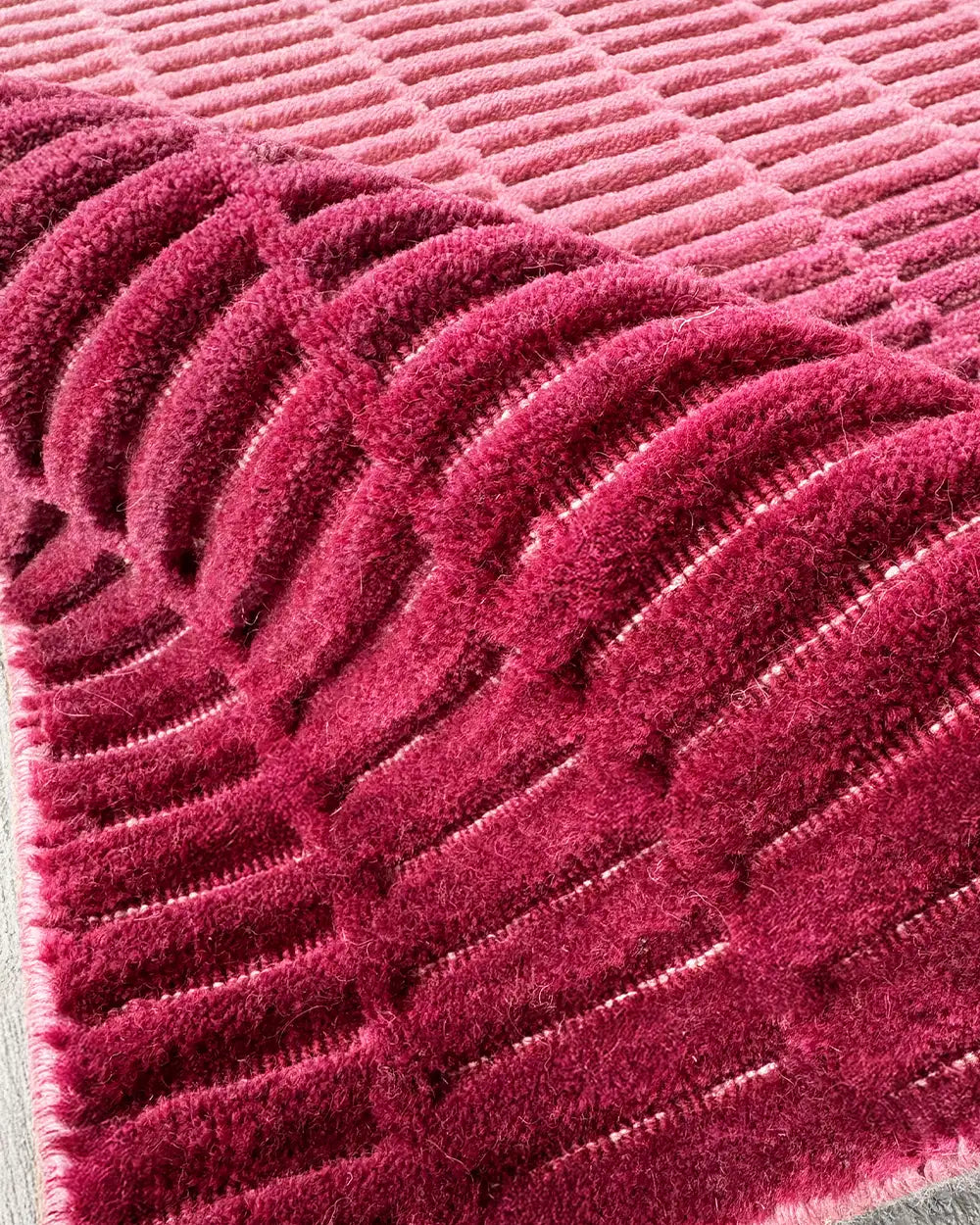 close-up texture view of a deep pink wool loomed rug with ridged ombre pattern