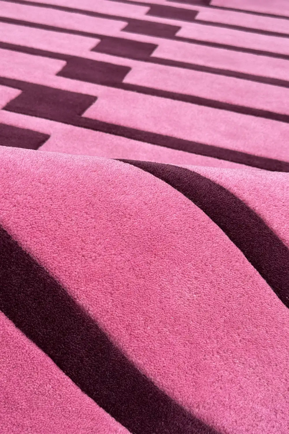 Close-up of a pink and purple textured wool rug with geometric patterns.