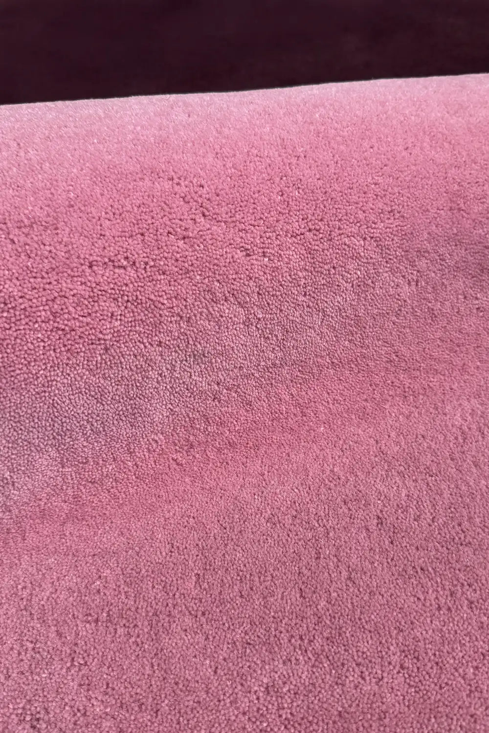 Soft pink and plum block rug surface close-up, purple and pink nursery rug or boho area rug with cozy feel