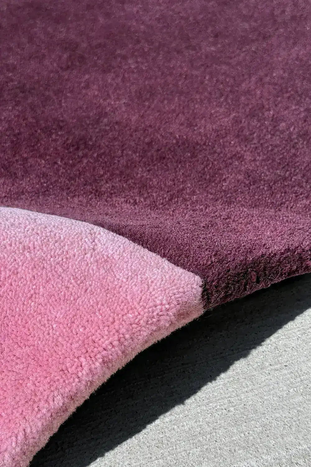 Colorblock pink and purple area rug showing curved corner, wool rug in blush and mauve tones for bedroom or office