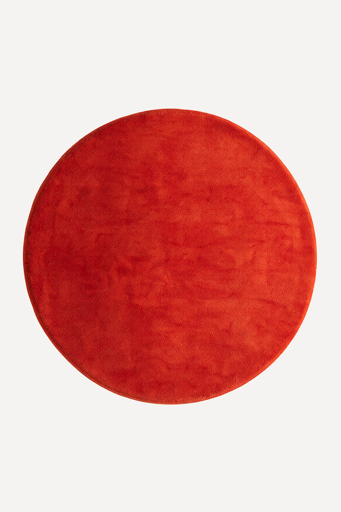 Red round wool rug on a white background