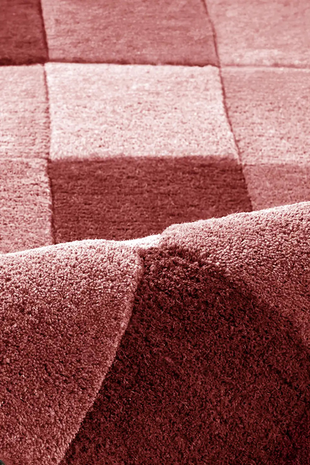 texture detail of hand tufted burgundy checkered wool rug in warm tonal palette