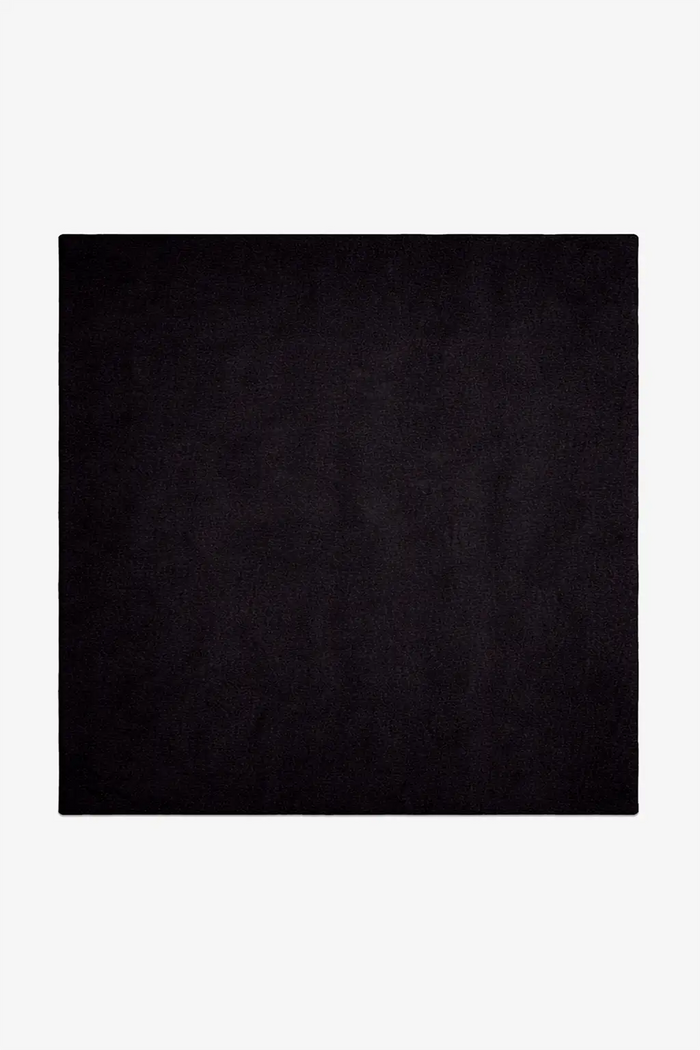 Solid black square rug hand-tufted in wool on a white background